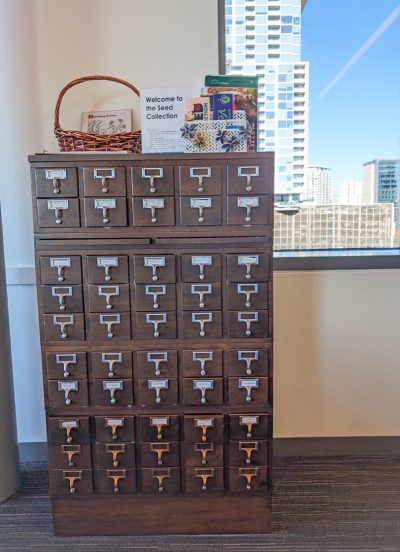 seedcatalog card catalog wooden drawer shelf in front of window overlooking city buildings