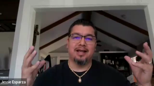 Dr. Jesus Esparza, historian at Texas Southern University, speaks and gestures with both hands during a video call from inside his home.